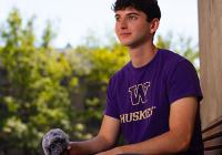 Leo Freedman sitting on a bench on campus, with a microphone in his hand.